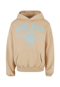 Sweat à capuche beige avec grand texte bleu « "Karl Kani The Original Street Academy" » et motif d’aigle bleu sur la poitrine.