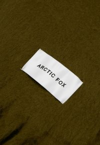 Olivgrüner Stoff mit einer weichen, strukturierten Oberfläche; enthalten ist ein weißes Etikett mit der Aufschrift "ARCTIC FOX" in schwarzer Schrift.