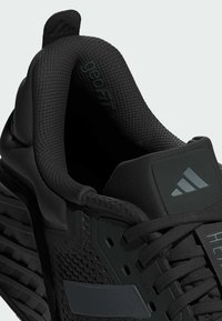 Black athletic shoe featuring a textured upper, cushioned collar, prominent lacing system, and molded accents. Designed for performance.