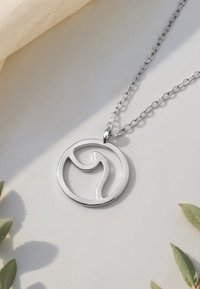 Söljhänge med cirkulär design och ett abstrakt vågmönster. Fäst vid en länkad silverkedja.