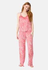 Rosa blommig pyjamaset med ärmlös topp med spetsdetaljer och löst sittande byxor, båda med ett tropiskt blad- och blommönster.