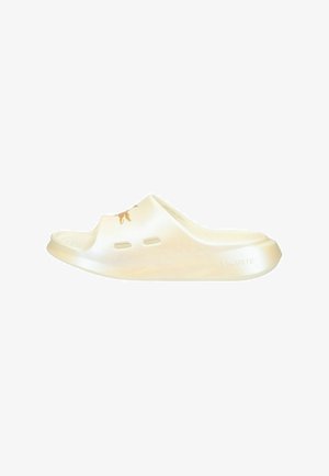 Sandale slide beige à bout ouvert avec des trous de ventilation et un logo crocodile sur la bride supérieure, avec une semelle intérieure et un talon texturés.