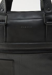 Fekete bőrbőrönd, dombornyomott "bugatti" logóval, fém karikákkal, cipzáras zsebbel és texturált alsó panellel.