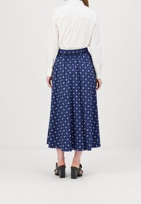 La skirti midi floral navy kun la elasta talio, kun malgrandaj rozaj kaj blankaj floroj, estas kunmeta kun blanka buton-supraj ĉemizo kaj blok-ĉapitraj ŝuoj.