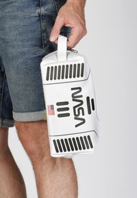 Bolsa rectangular blanca con un asa, con detalles en negro, un logo de la NASA y una bandera americana. Hecha de material sintético con una textura suave.