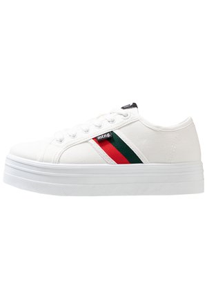 Baskets en toile blanches avec une semelle plateforme, dotées d'un accent rayé vert et rouge et d'une étiquette de logo noire près des lacets.