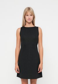 Black sleeveless dress made of ribbed fabric, featuring a round neckline and a fitted design that flares slightly at the hem.