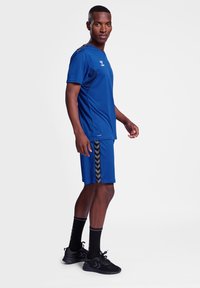 Conjunto de camiseta atlética azul y pantalones cortos con acentos laterales negros. Fabricado en material suave, con cuello redondo y mangas cortas.