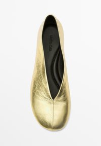 Guld läderballettskor med spetsig tå. Det texturerade ovandelen har en slät yta, och innersulan är svart med varumärkeslogotyp.