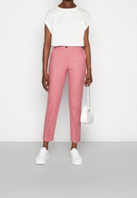 Rosa skräddarsydda byxor med slim fit och fickdetaljer fram, tillsammans med en vit kortärmad topp och vita sneakers. Liten vit handväska ingår.