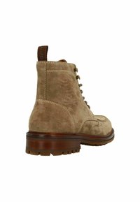 Tan suede enkellaarsjes met een ronde neus, vetersluiting aan de voorkant en een bruine rubberen zool. Voorzien van een trekband aan de achterkant en contrasterende stiksels.