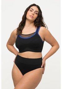 Czarny stanik sportowy z niebieskimi wykończeniami i siateczkowymi detalami, w połączeniu z czarnymi spodniami o wysokim stanie. Gładki materiał o strukturze.