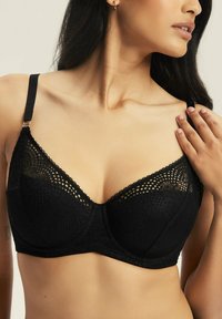 Czarny koronkowy biustonosz z fiszbinami, z dekoltem w kształcie litery V i kwiatowym wzorem. Regulowane ramiączka, strukturalny materiał i gładkie miseczki.