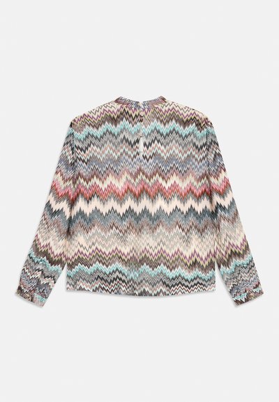 Blusa a maniche lunghe con un motivo a zigzag multicolore in tonalità di blu, rosso e crema. Dettaglio con apertura a chiave sul retro con chiusura a bottone.