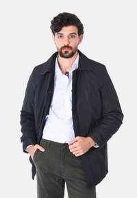 Giacca leggera blu navy con colletto e tasche frontali. Realizzata in materiale liscio, con chiusura a bottoni e linee pulite.