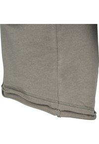 Gros plan d'un ourlet de vêtement en tissu gris avec couture visible et détail de bord plié.