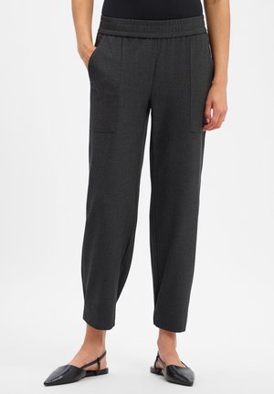 Dunkelgraue gerade geschnittene Hose mit elastischem Bund und aufgesetzten Vorderentaschen, getragen von einer Person, die mit den Händen in den Taschen steht.