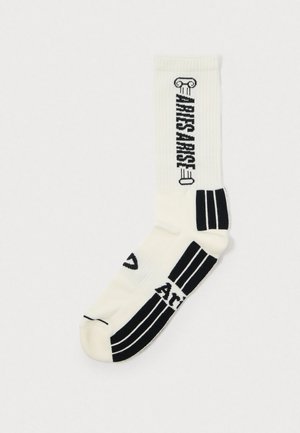 Fehér bokazokni fekete grafikai mintákkal, beleértve az "ARTISAN" feliratot és három fekete csíkot a bokánál. Bordázott textúrájú.