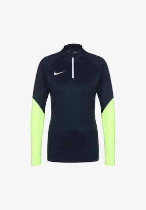 Zwart atletisch shirt met lange mouwen en neongele onderarmen, witte Nike-swoosh op de borst en korte ritssluiting aan de voorkant.