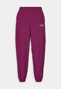 Lila Nike Sportswear träningbyxor med elastisk midja och muddar, med en vit swoosh-logga på övre vänstra låret.