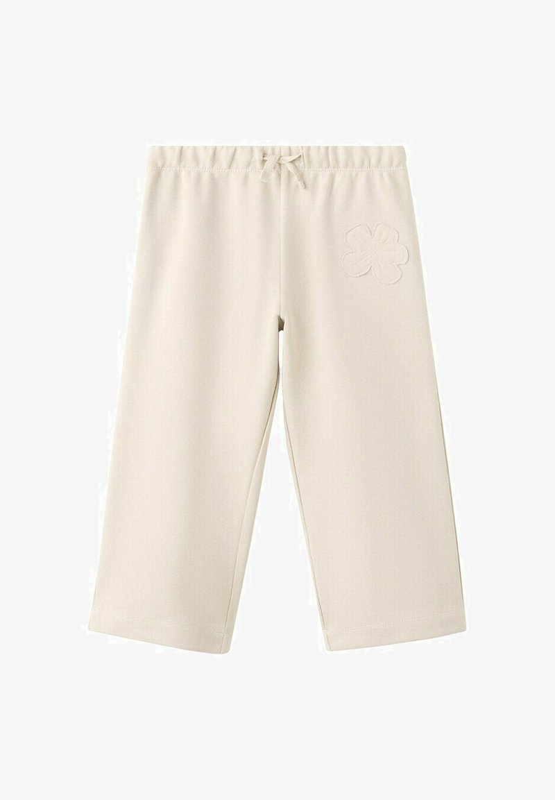 Široke hlače krem barve z elastičnim pasom, vrvico in našitkom v obliki cvetlice na zgornjem desnem stegnu.