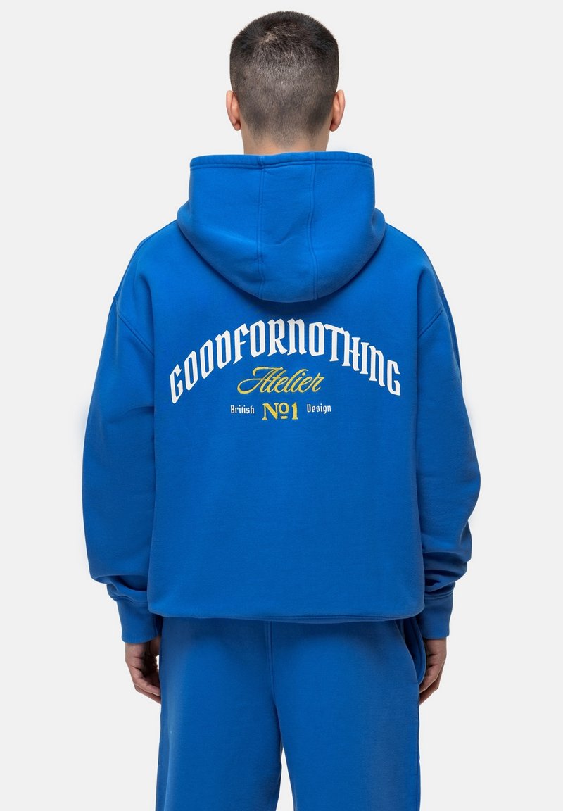 Felpa in cotone blu con una vestibilità ampia. Presenta un grande testo bianco e giallo sul retro. Il testo include "GOODFORNOTHING" e "Atelier."