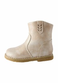 Ljusbeige ankelskor med en texturerad läderfinish, böjda sid sömmar och en dekorativ utskärning bak. Gummisula.