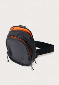 Borsa a tracolla nera in tessuto con interno arancione, dotata di due scomparti con zip, tracolla regolabile e dettagli di cucitura a contrasto.