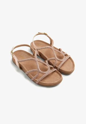 Par de sandalias planas beige con suelas acolchadas y tiras cruzadas brillantes, con hebillas ajustables en el tobillo.