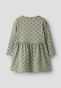 Φόρεμα με μακριά μανίκια από απαλό ριπ ύφασμα, ελιάς πράσινο με ναυτικό πουά, φούστα σε σχήμα καμπάνας, στρογγυλή λαιμόκοψη και ελαφρώς σούρες στη μέση.