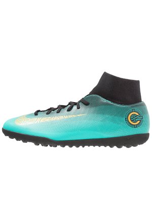 Scarpa da calcio turchese e nera con swoosh e logo dorati, con lacci neri e colletto alla caviglia simile a un calzino nero.