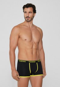 Boxers de algodón negros con acentos amarillos y cinturilla con logo, con un ajuste ceñido y detalles de costura en contraste.