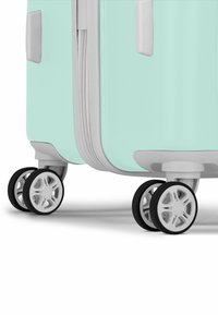 Turquoise hard-shell suitcase with a textured surface, grey accents, and four multi-directional wheels. Zipper closure visible.
