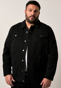 Svart denimjacka med knappstängning framtill, två bröstfickor och silverdetaljer. Har en klassisk krage och ribbad textur.