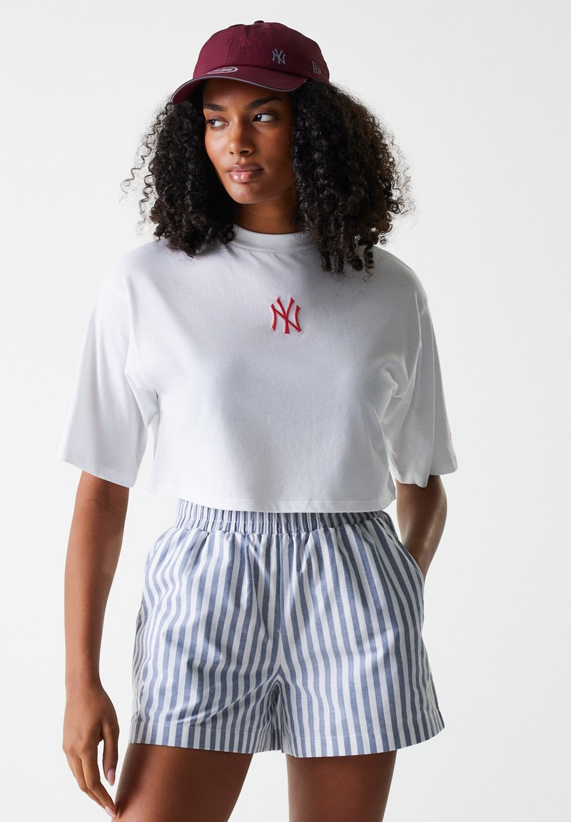 White cropped t-shirt with red NY logo, paired with blue and white striped shorts featuring an elastic waistband. Also includes a burgundy cap.