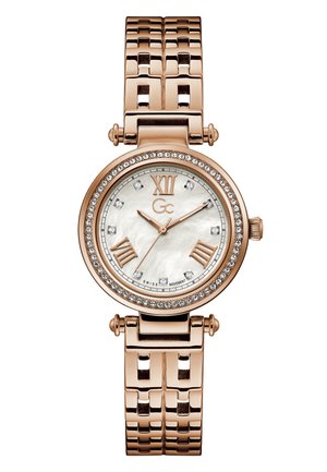 Rožu zelta pulkstenis ar apaļu korpusu, pērlītes ciparnīcu, romiešu cipariem, kristāla akcentiem un salikta rokassprādze.