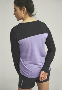 Long-sleeve athletic top with a black upper section and a lavender lower section. Lightweight fabric with a smooth texture.