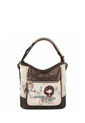 Braune und beige Handtasche mit einem Cartoon-Mädchen, einem Fahrrad, einem kleinen Hund und dem Text "time to bloom" auf der Vorderseite mit dekorativen Anhängern.