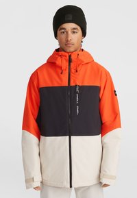 Chaqueta con bloques de color que presenta paneles en naranja, negro y crema. Fabricada con material sintético, con cierre de cremallera en la parte delantera y capucha ajustable.