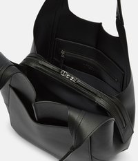 Czarna skórzana torba typu tote o gładkiej strukturze, otwarta od góry, z wewnętrzną kieszenią na zamek oraz wieloma przegródkami do organizacji. Akcenty z srebrnego metalu.