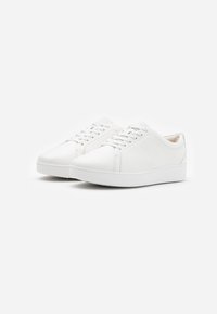 White synthetic sneakers with a smooth texture, rounded toe, and flat sole. Features lace-up design and subtle stitching details.