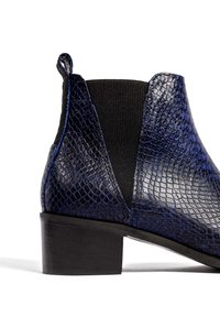 Niebieskie botki na kostkę z wężowej skóry z czarną elastyczną wstawką, niskim, podniesionym obcasem i teksturowaną powierzchnią. Zawierają zaokrąglony nosek oraz pętelkę z tyłu.