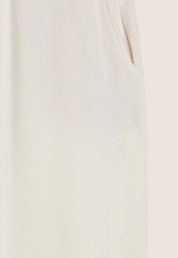 Robe sans manches en crème clair avec un tissu doux, dotée d'une poche latérale et d'un logo "FREDDY" en relief de couleur assortie.