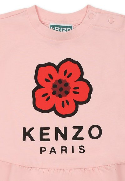 T-shirt en coton rose avec un grand motif de fleur rouge aux contours noirs et le texte "KENZO PARIS" en noir en dessous.