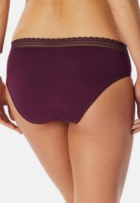 Sous-vêtements en coton bordeaux avec une bordure en dentelle le long de la taille. Présente un design couvrant et une texture lisse.