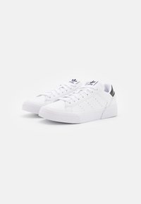 Bílé tenisky s texturovanou gumovou podrážkou, hladkým koženým svrškem a perorovanými detaily. Černý akcent na patě; plochý design na šněrování.