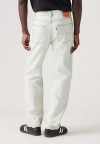 Jasnoniebieskie dżinsy o prostym kroju, z kontrastowym przeszyciem i dwiema tylnymi kieszeniami z metką logo Levi's. Proste czarne trampki.