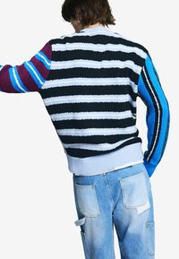 Farebný pletený sveter s horizontálnymi pruhmi v čiernej, bielej a žiarivej modrej farbe, s textúrovaným povrchom a rebrovaným lemom.