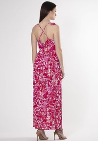 Maxi kjole med blomstermønster i pink og hvid, med tynde krydsede stropper og en svajende nederdel. Letvægtsstof.