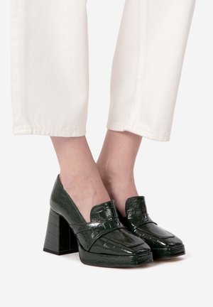 Mørkegrønne patenterede læderblokhælede sko med et krokodilleskinds mønster, der har en bred rem og rektangulær tådesign.